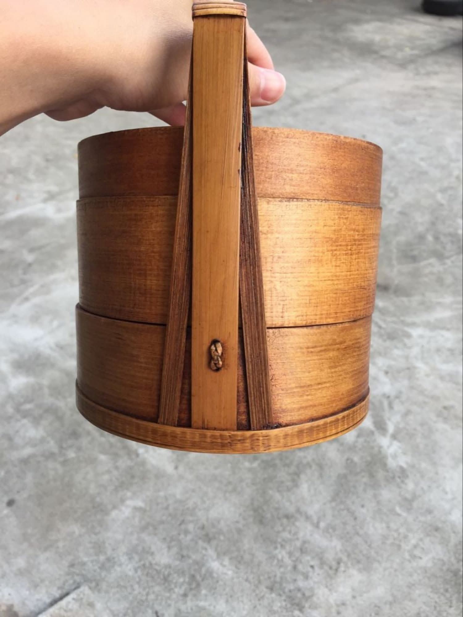 Natural wood Japanese lunch box with tiered compartments and handle.