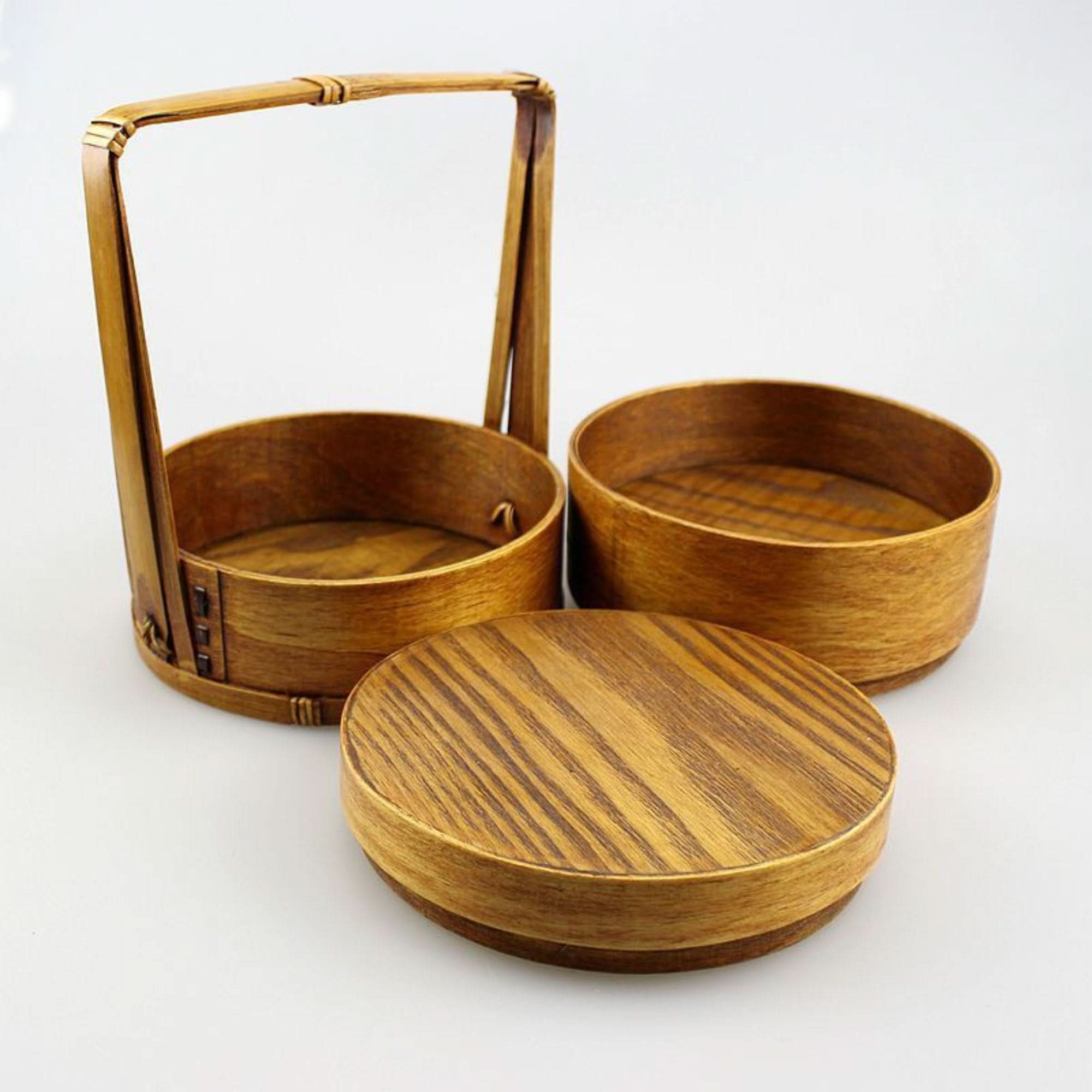Natural wood Japanese lunch box with a handle and two stackable containers, set on white.