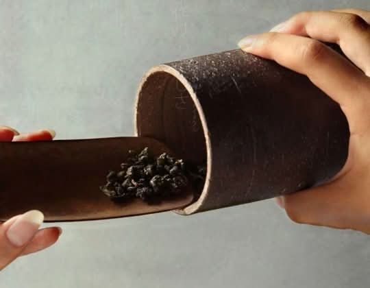 Japanese Style Raw Rustic Tea Jar scooping dried tea leaves. Dark brown, rustic texture.