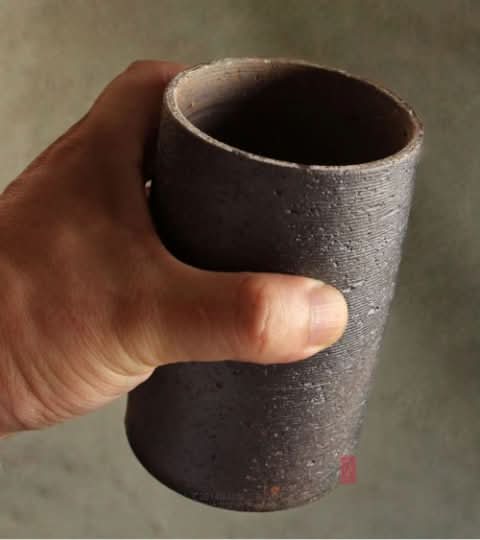Rustic Japanese style raw storage jar held in hand, dark ceramic, ideal for tea, coffee, sugar.
