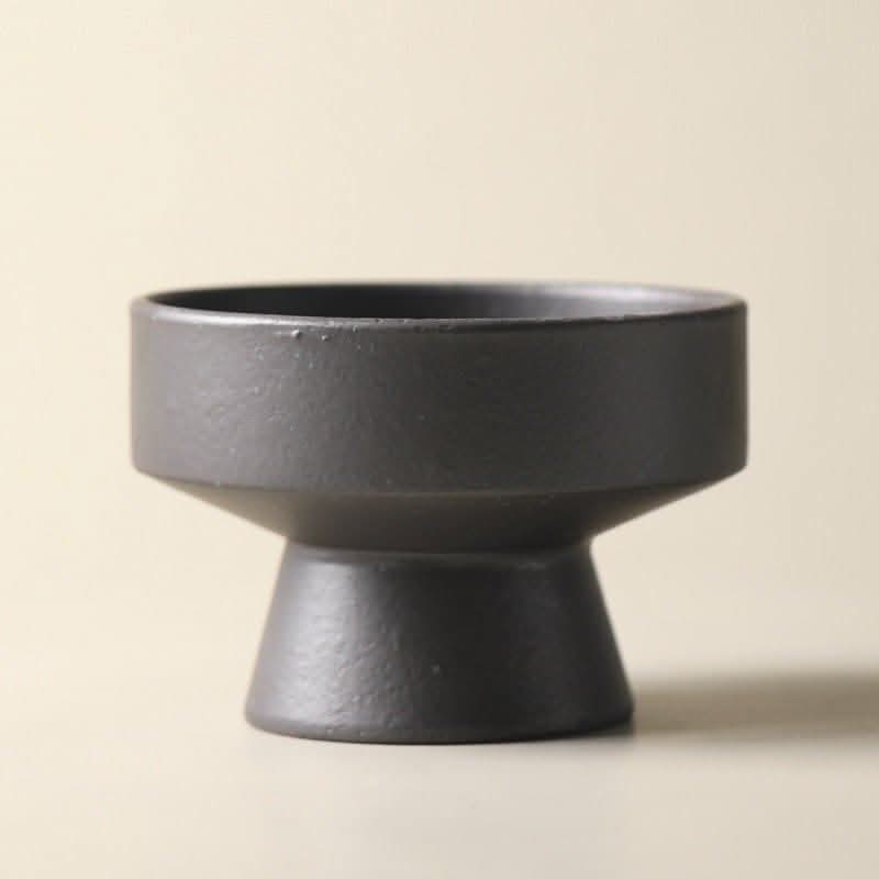 Dark grey Japanese style stoneware fruit plate with a pedestal base on a neutral background.