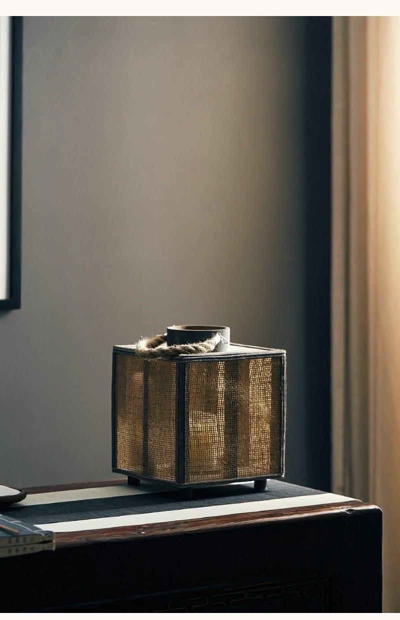 Rustic jute and dark metal Coastal Candle Holder with rope accent on wooden surface.