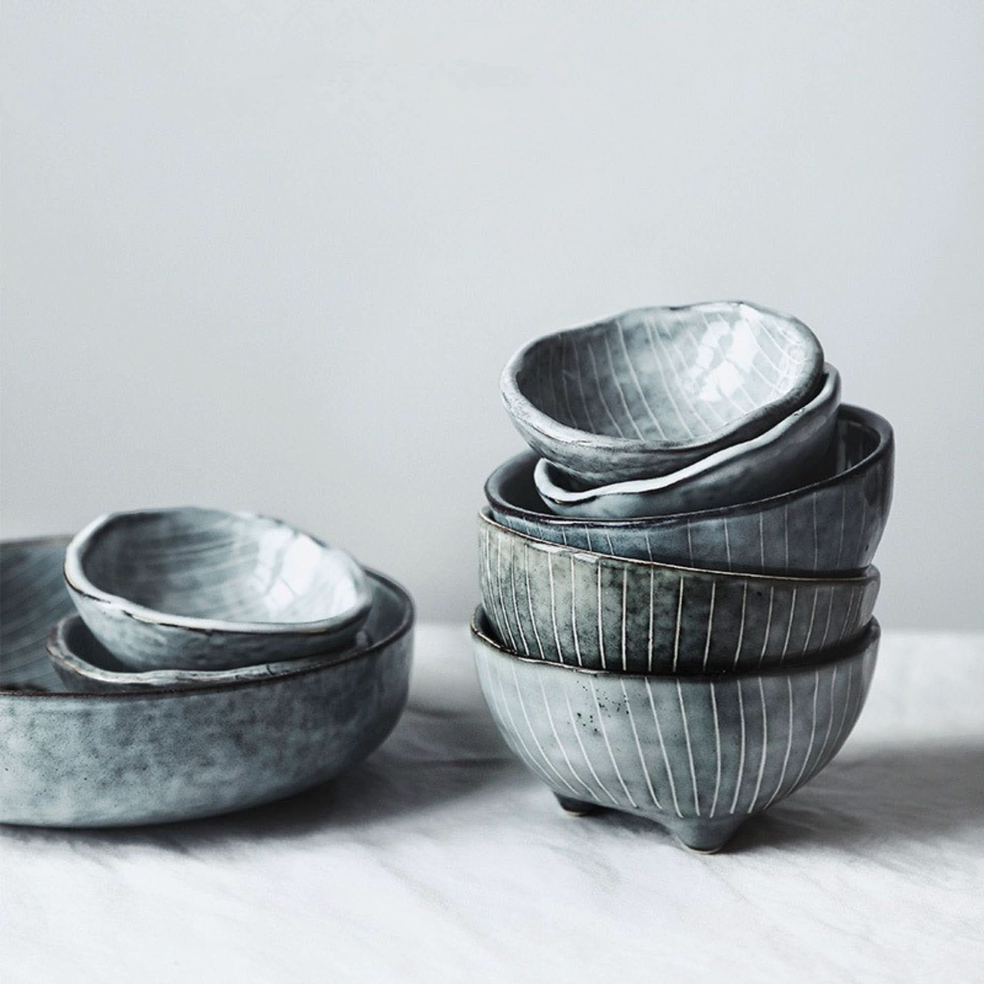 Grey Japanese tableware ceramic set with textured finish and vertical line detail on white cloth.