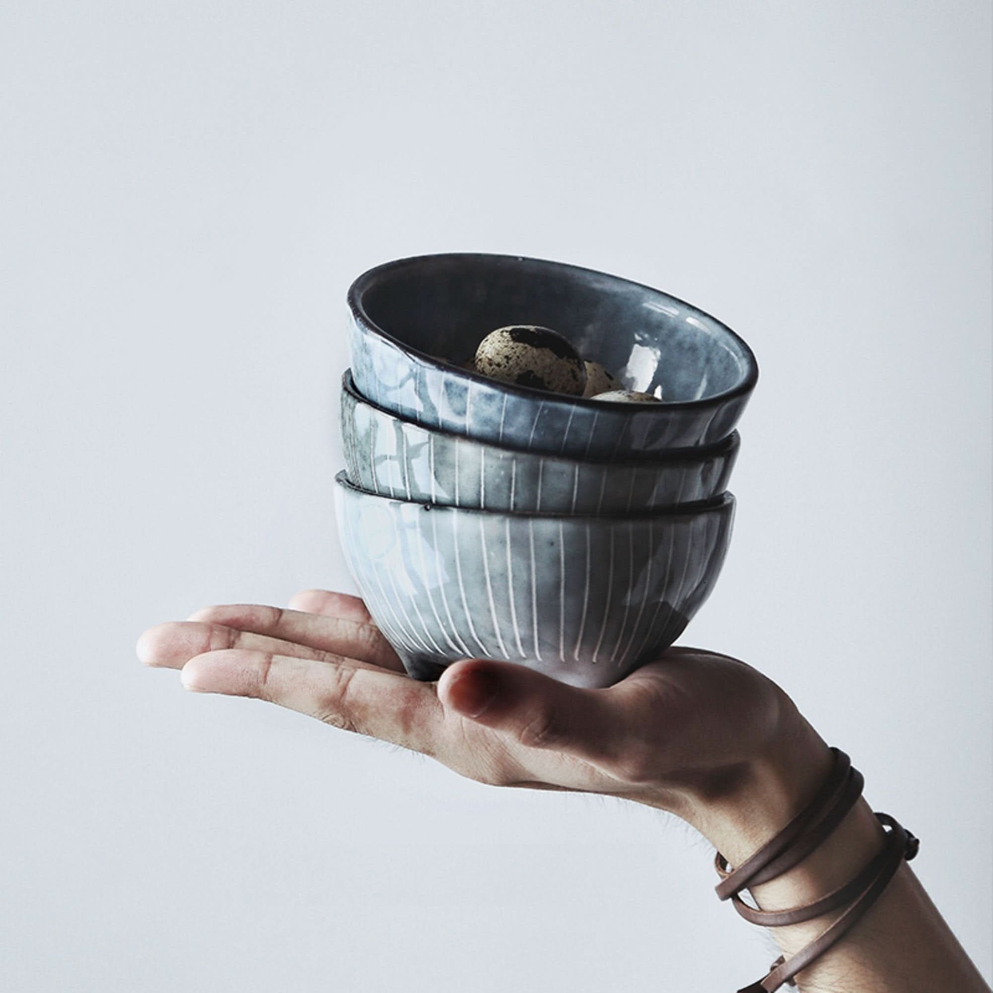 Stack of grey ceramic bowls with subtle stripes, part of a Japanese tableware set.