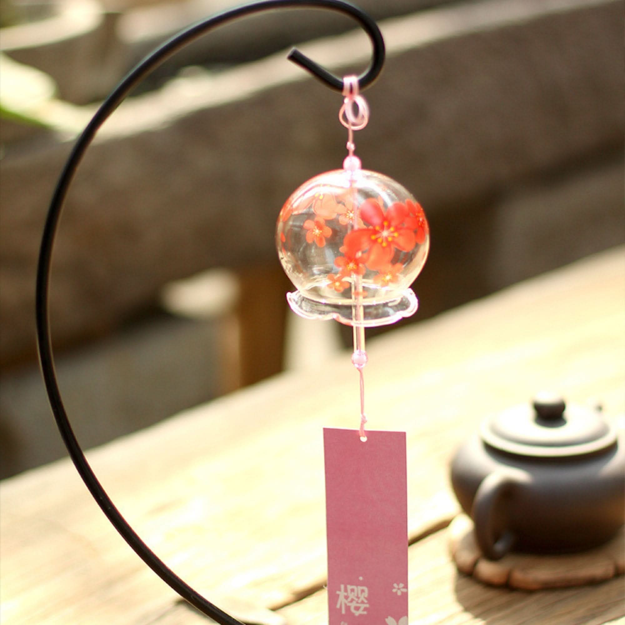Glass Japanese wind chime with red floral pattern, on display with a teapot.