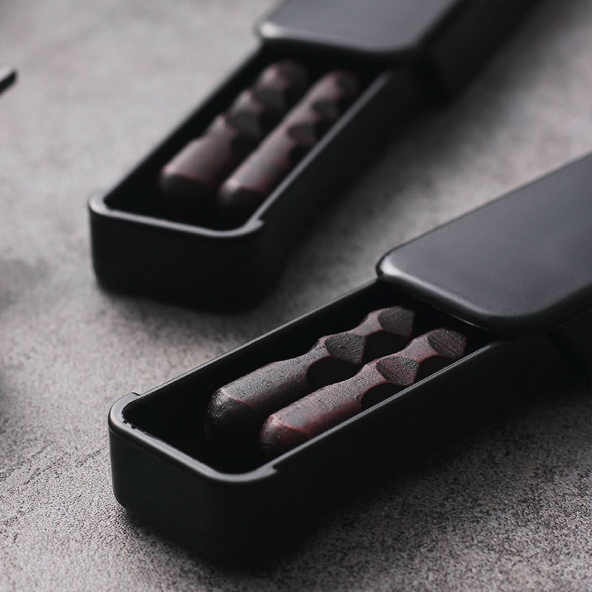 Natural wooden Japanese chopsticks with case and spoon set on a textured grey surface.
