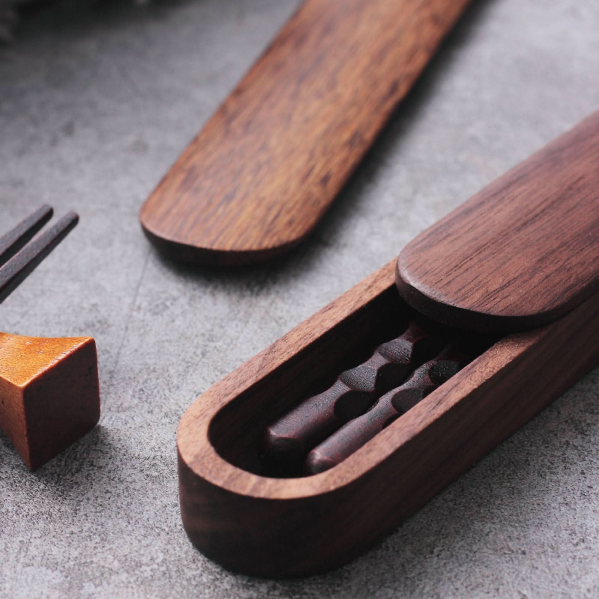 Natural wooden Japanese chopsticks with case and spoon set on textured surface.