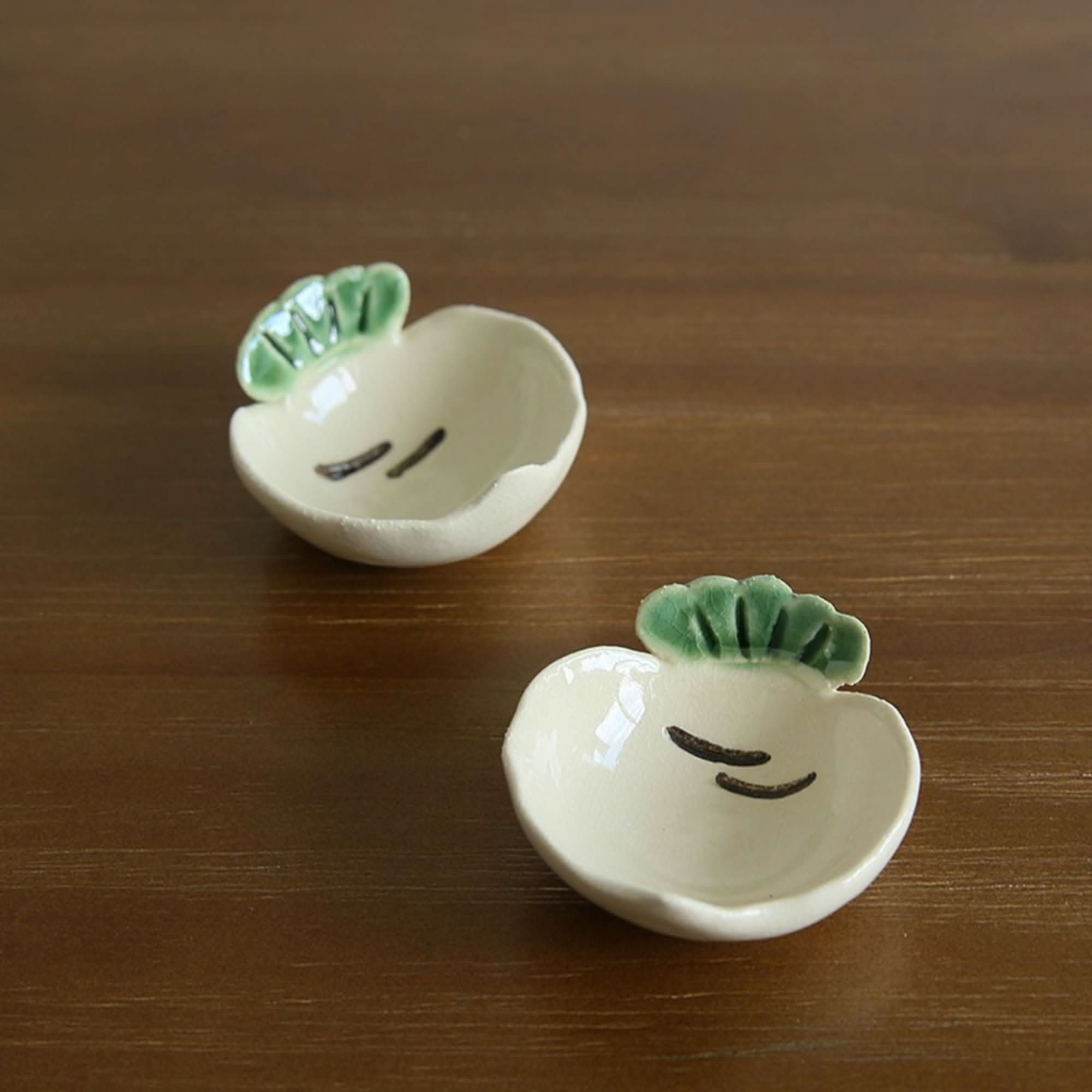 Mino-yaki handmade vegetable dip bowl in stoneware, white with green tops, on wood.