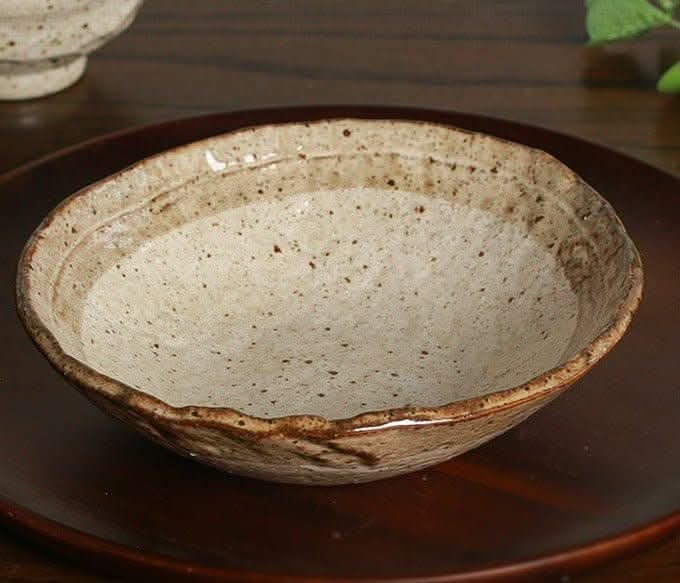 Minoyaki irregular ceramic soup bowl, speckled earth tones on a dark wooden surface.