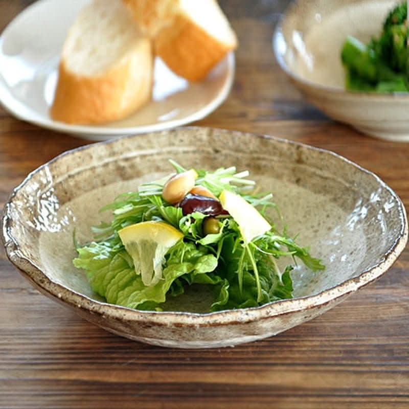 Minoyaki irregular ceramic soup bowl with fresh salad and lemon slices on rustic table.