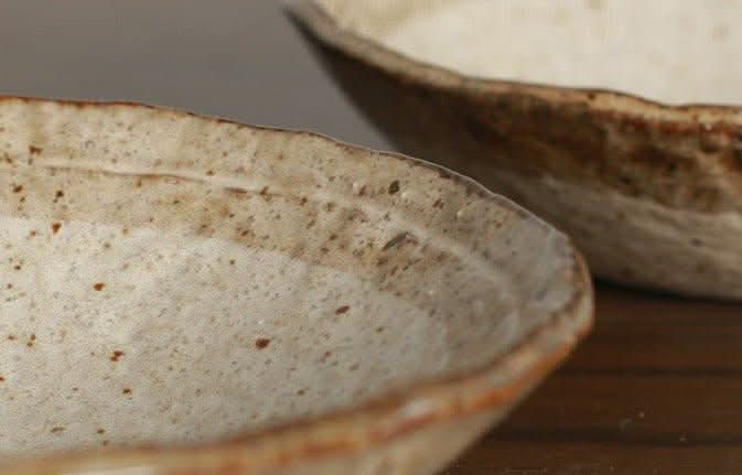 Minoyaki irregular ceramic soup bowl, speckled beige with brown rim, on wooden surface