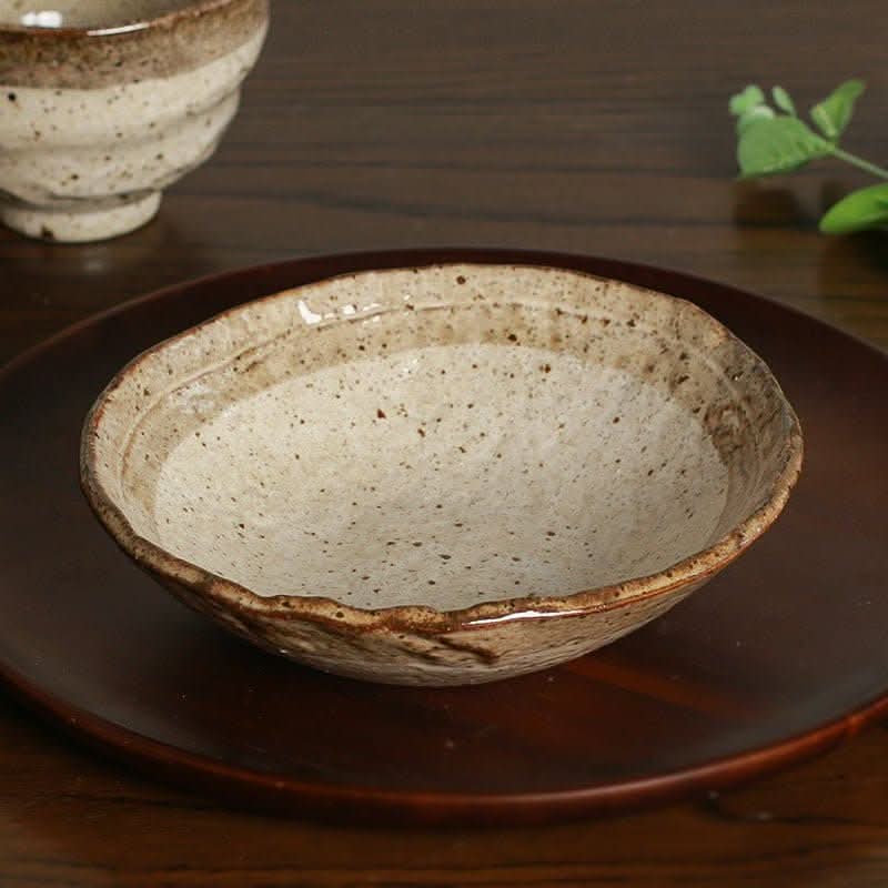 Minoyaki irregular ceramic soup bowl with speckled beige interior on dark plate.