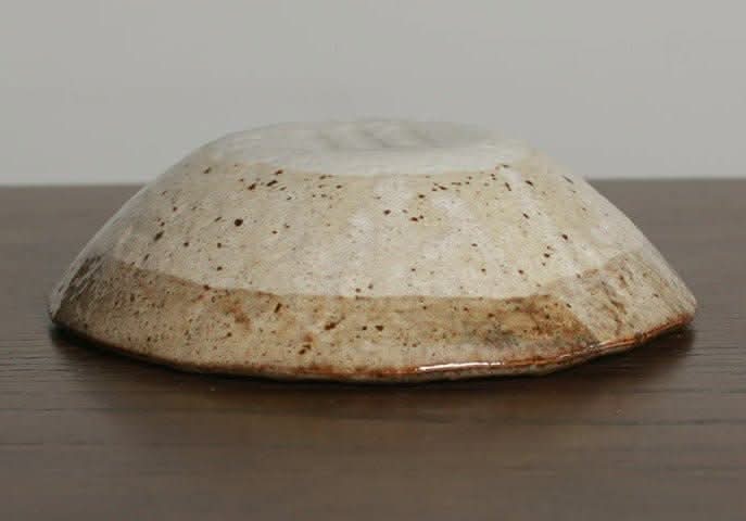 Minoyaki irregular ceramic soup bowl, speckled beige and brown glaze, on wooden surface.