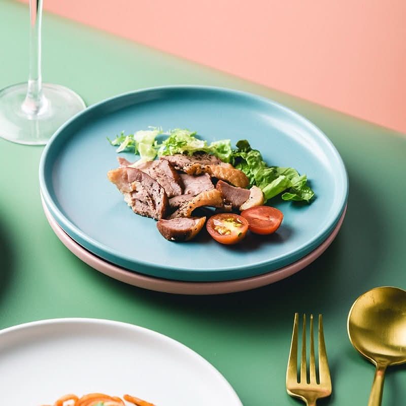 Multifunctional tray with matte blue glaze, holding sliced meat, lettuce, & tomatoes. Ceramic tableware.