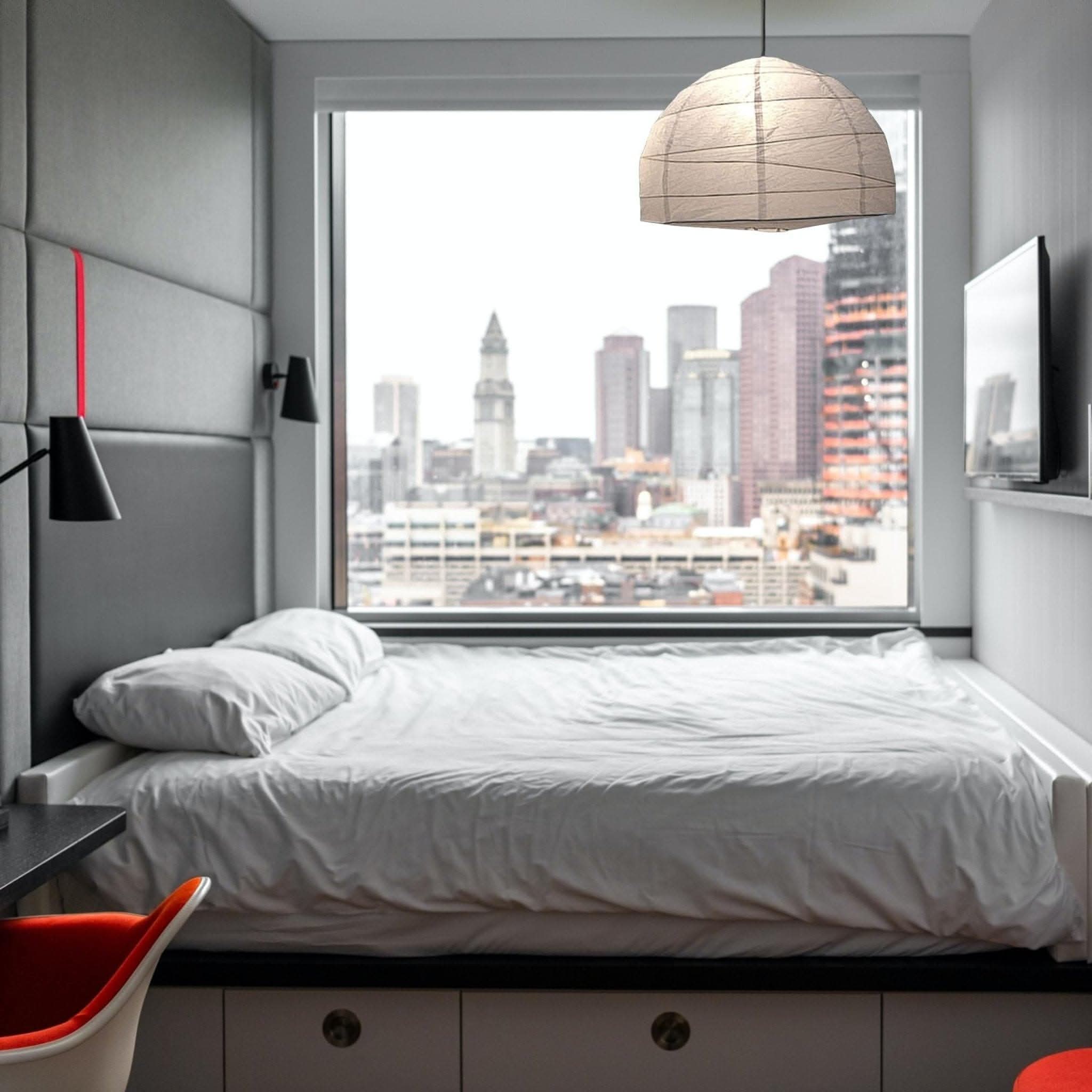 Paper Lampshade Oval Shape hangs above a modern bed with a city view.