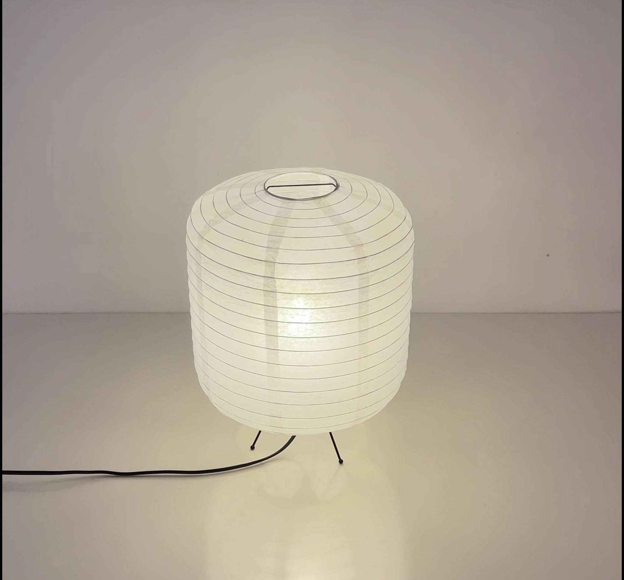 White paper table lamp with rounded cylinder shape on a clean surface.