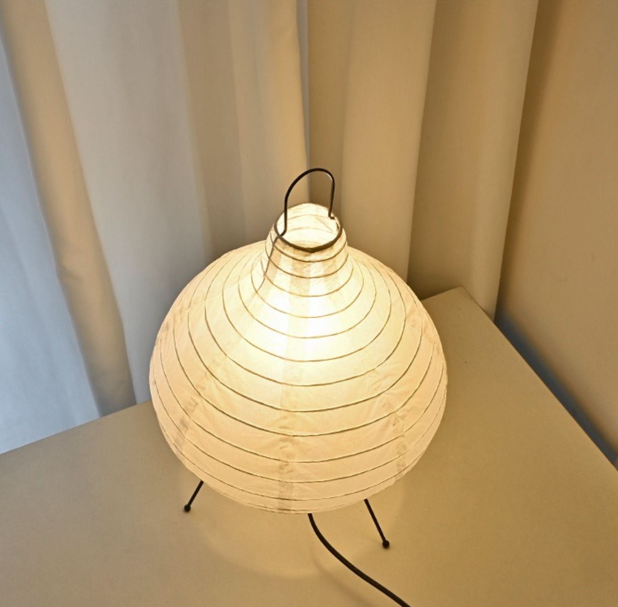 Paper table lamp, garlic shape, with mid-century Asian design on a white surface.