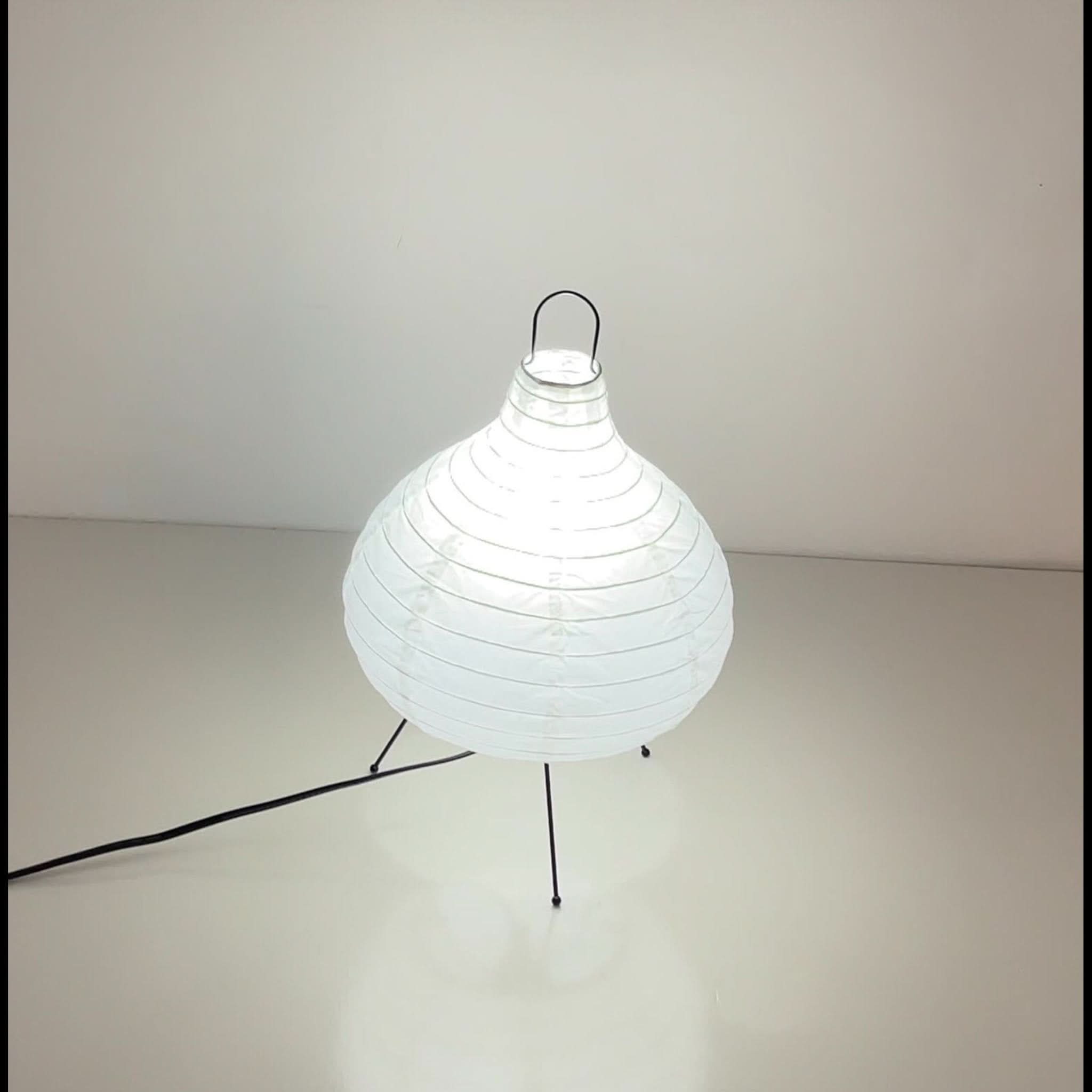 White paper table lamp in garlic shape on black legs, modern home decor.
