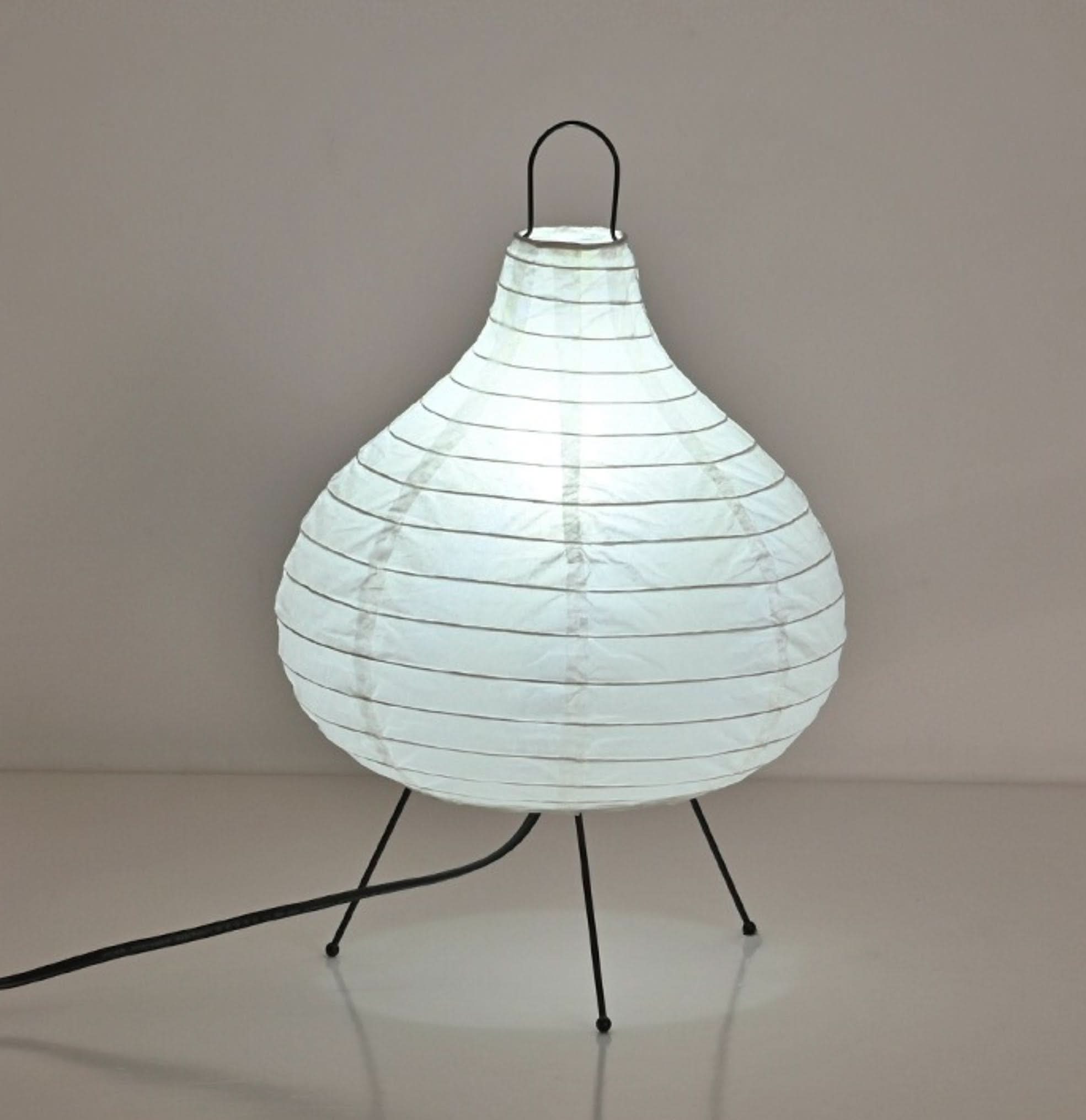 White paper table lamp with black legs, garlic shape.