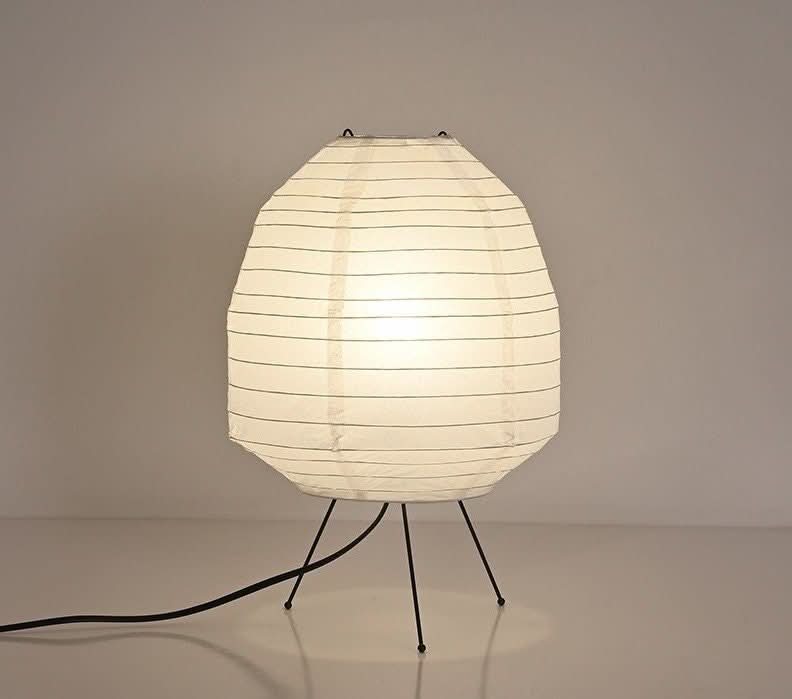 White paper table lamp with thin black lines on thin black legs.