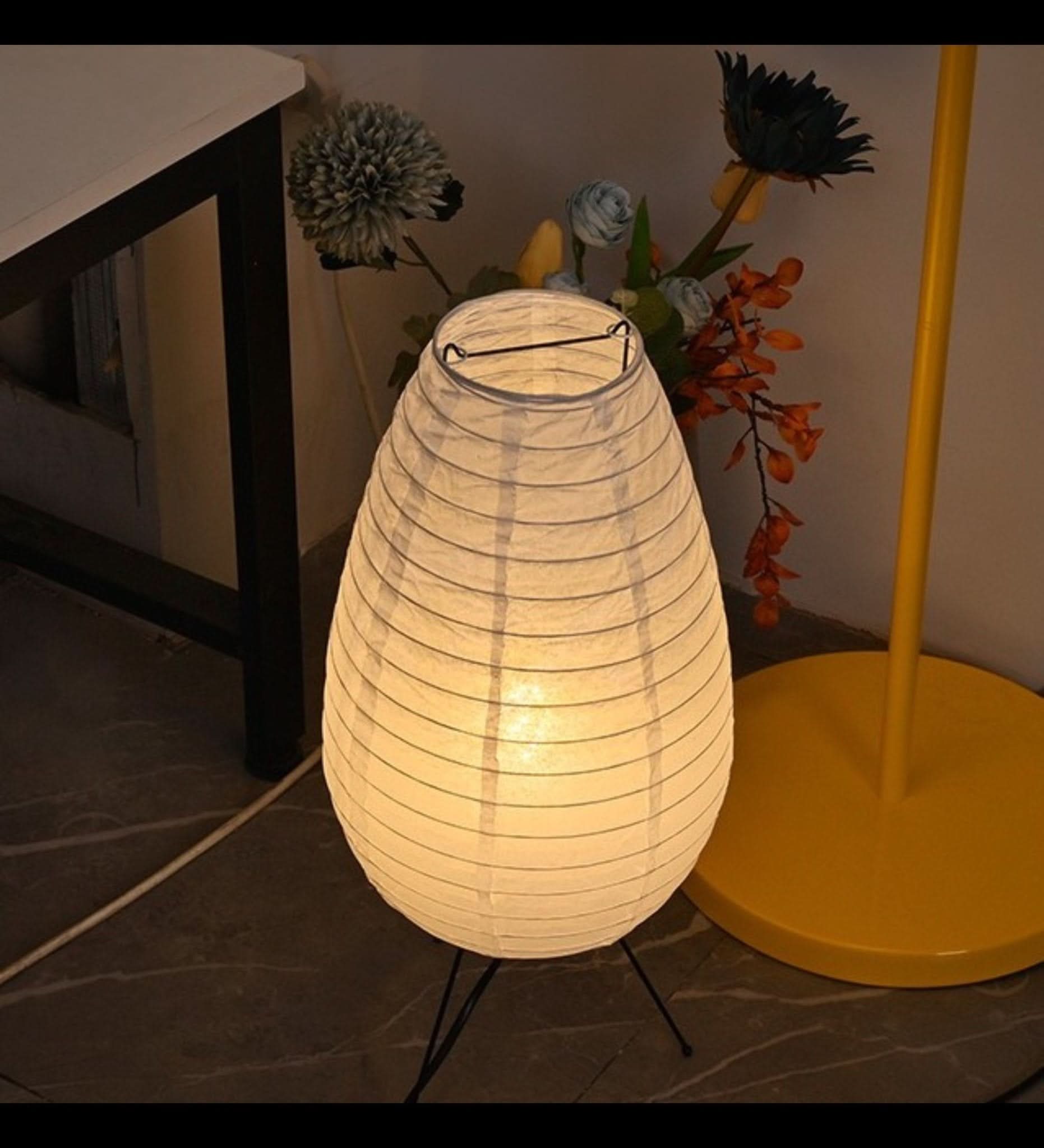 Paper Table Lamp Long Oval Lamp: lit white paper in teardrop shape on black tripod base.