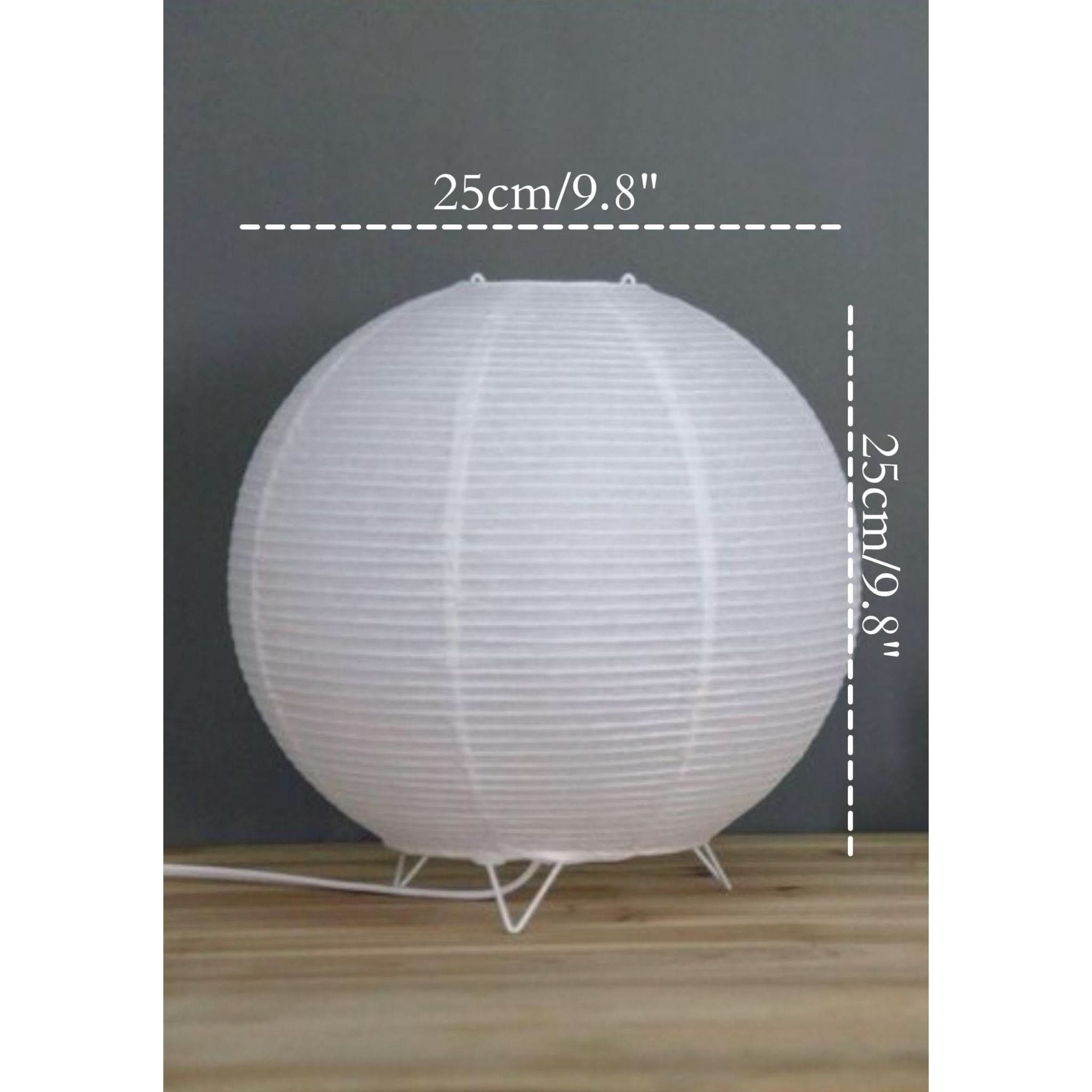 White paper table lamp on a wooden surface with a dark gray background.