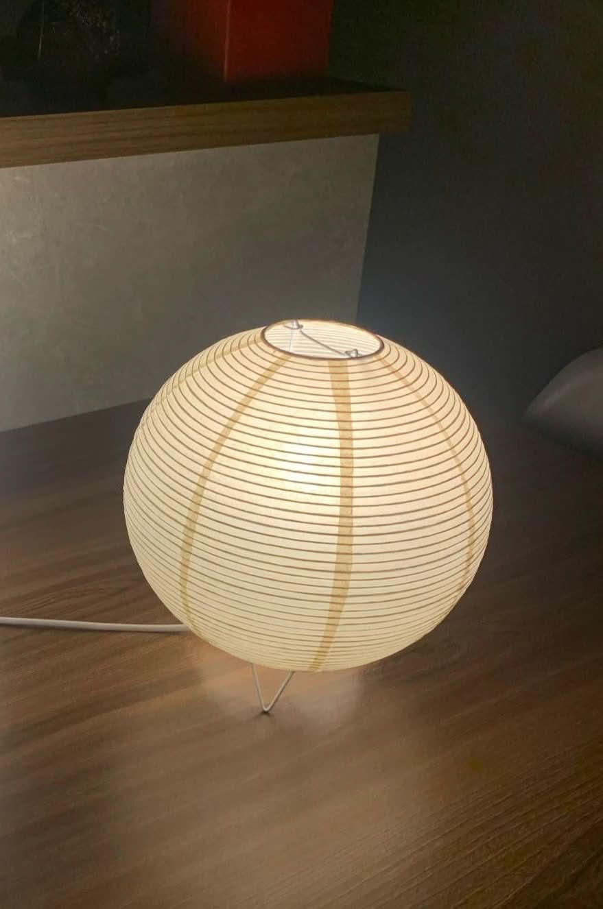 Paper Table Lamp Elongated with warm glow on wooden table.