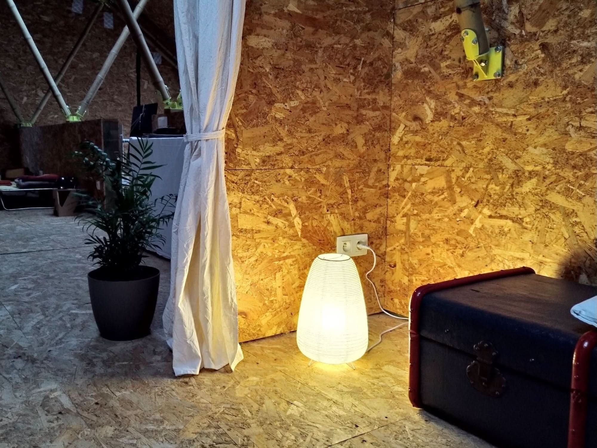 White paper table lamp, elongated design, illuminated, in a room with wood paneling.