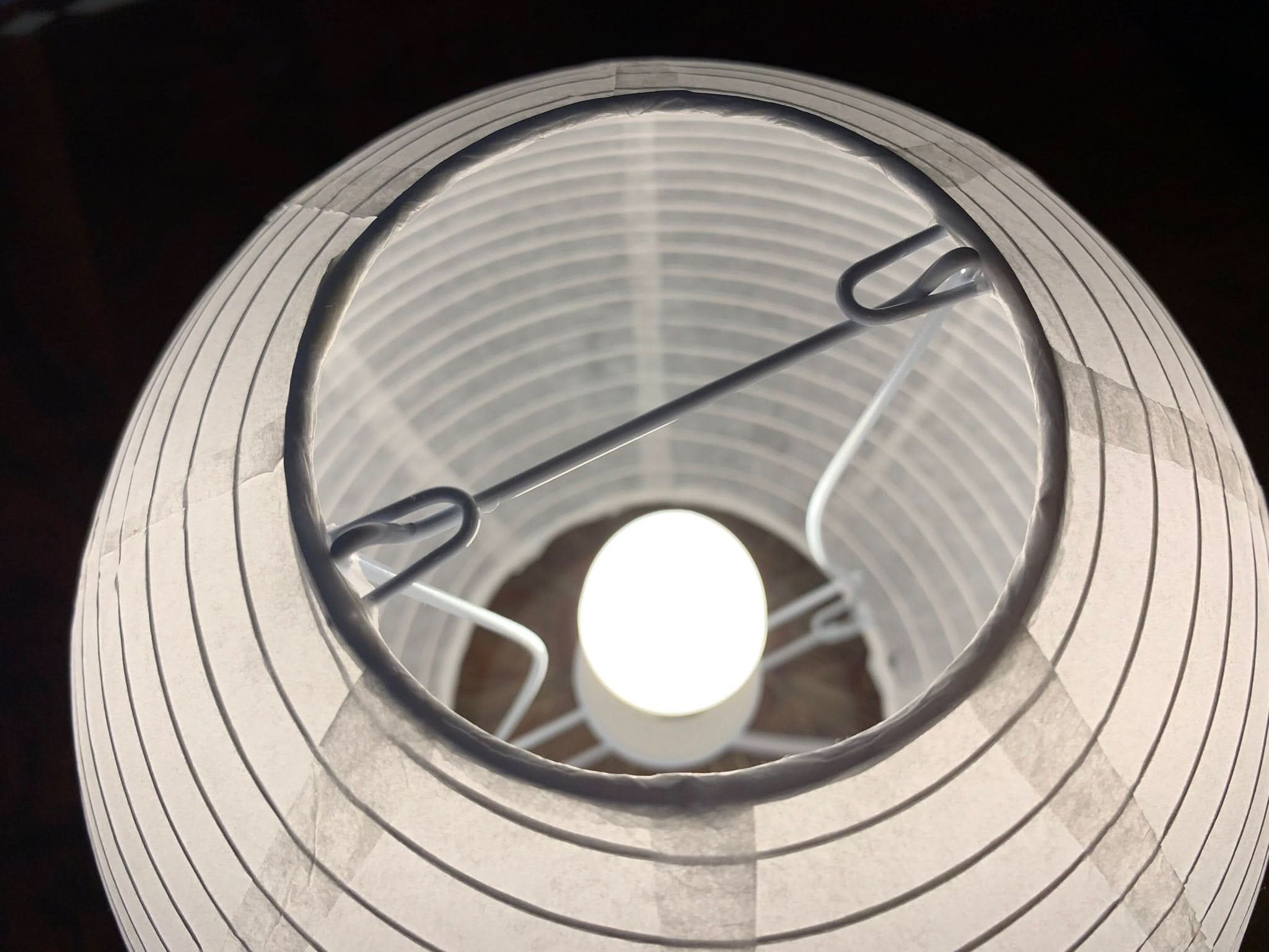 White paper table lamp with internal structure and illuminated bulb, home decor