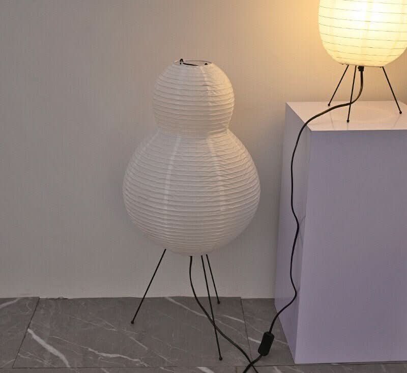 White paper floor lamp with pear shape on thin black legs, modern home decor.