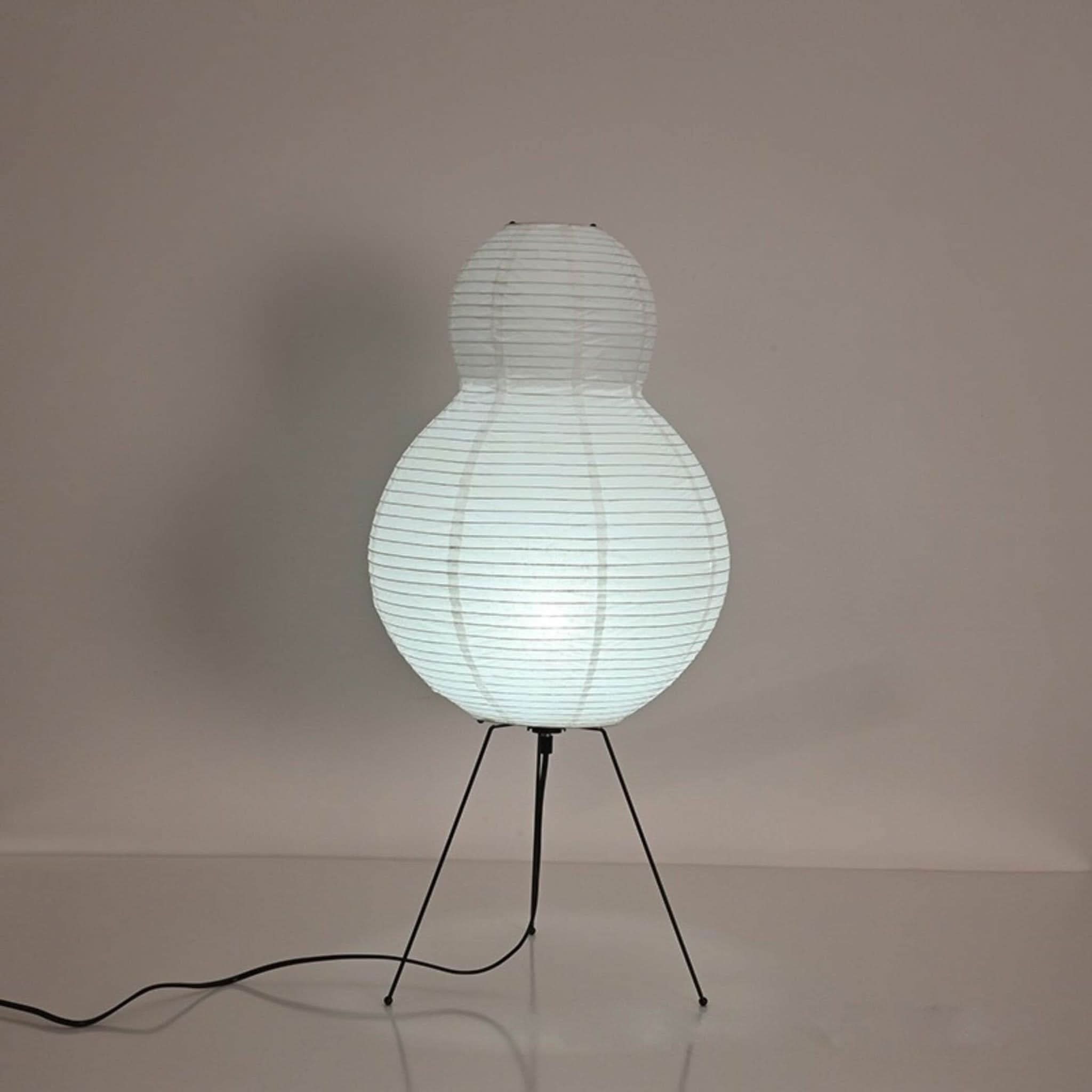 White paper floor lamp with pear shape on black tripod legs, home decor.