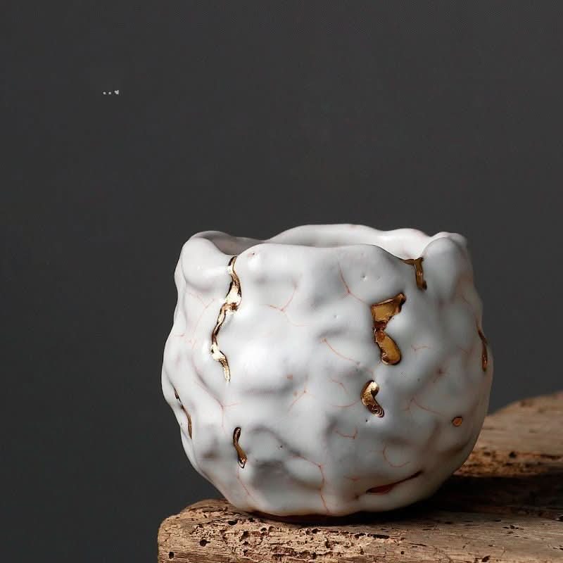Handmade Japanese Kintsugi tea cup: white porcelain with gold glazed cracks.