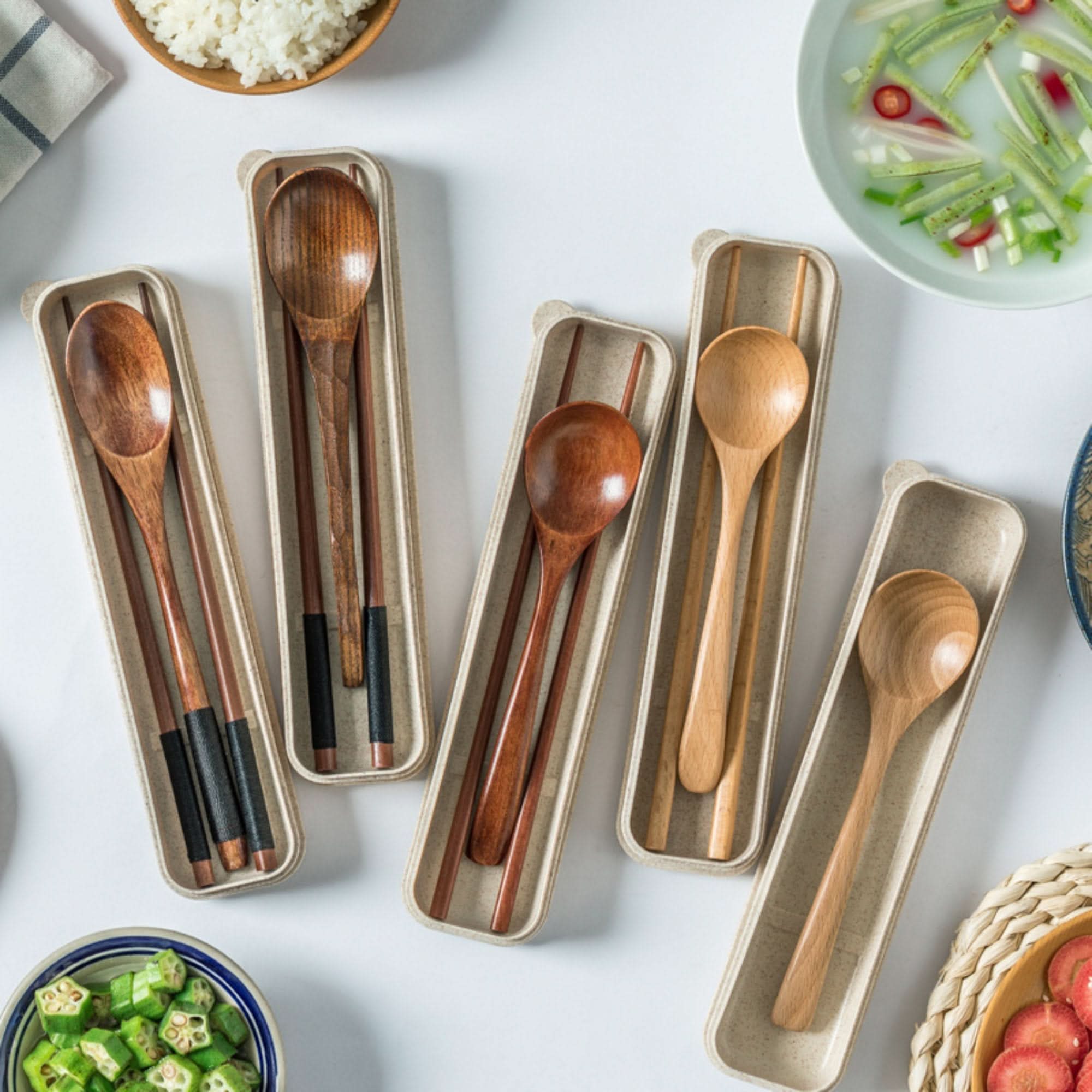 Natural wooden spoon sets and chopsticks in cases, part of a portable utensil set.