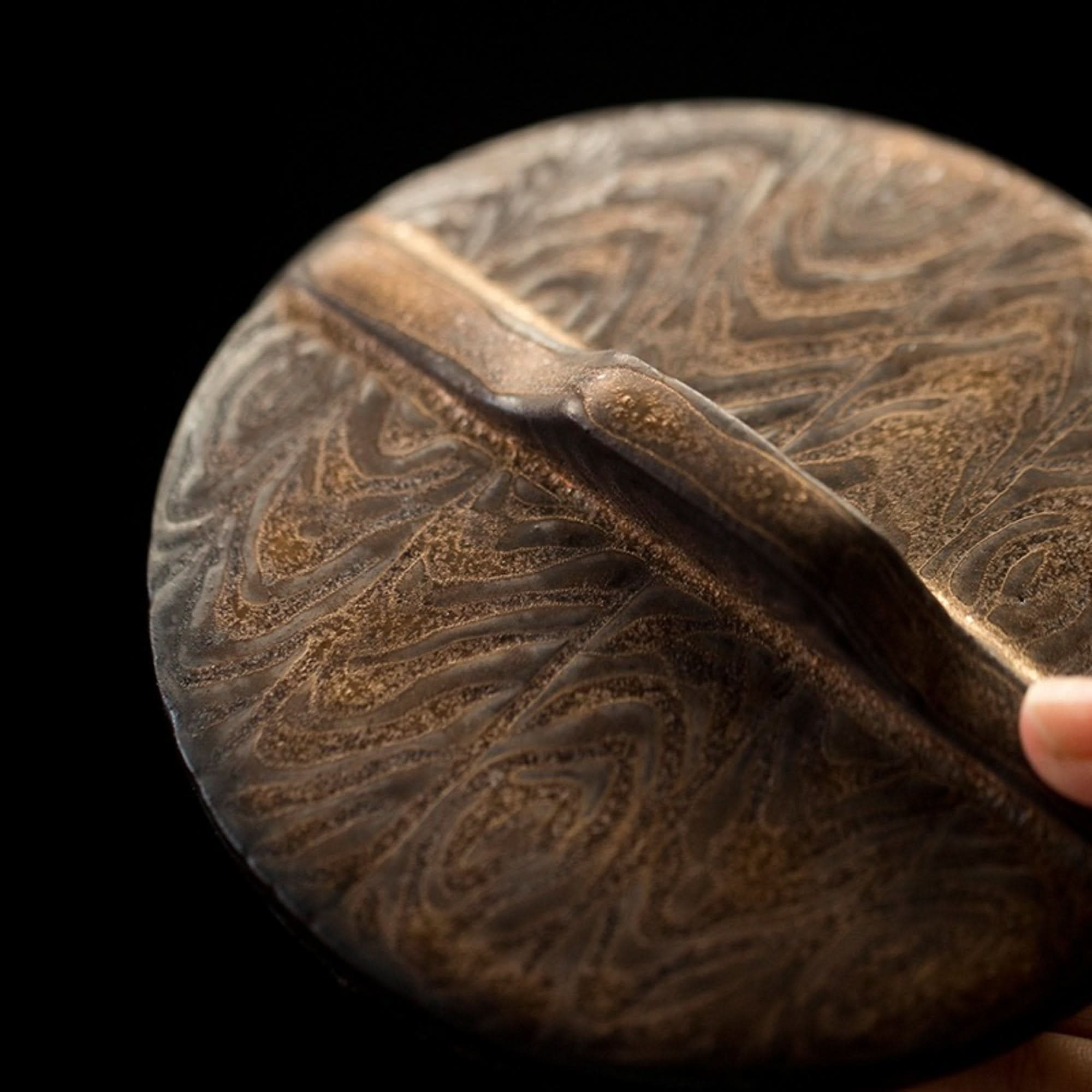 Brown pottery Japanese tea jar lid with intricate texture, vintage design.