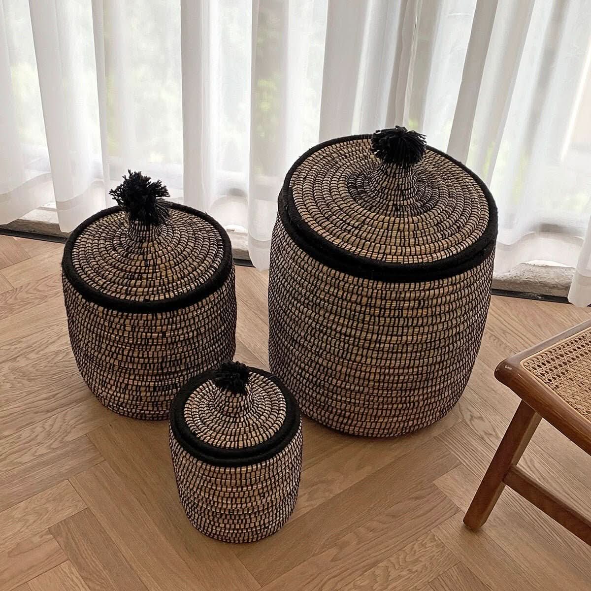 Set of three natural rattan baskets with lids and wool pom-poms, home decor storage.