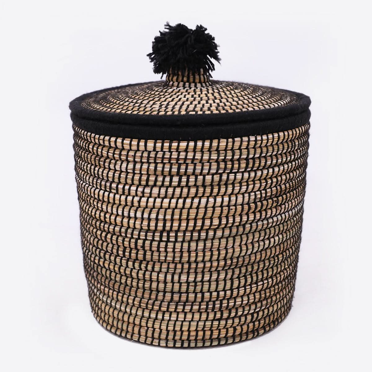Natural rattan basket with lid and black wool pom-pom accent. Home decor storage.