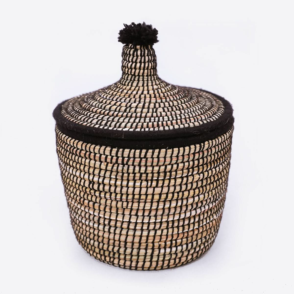 Black and natural woven rattan basket with lid and wool pompom, home decor accent.