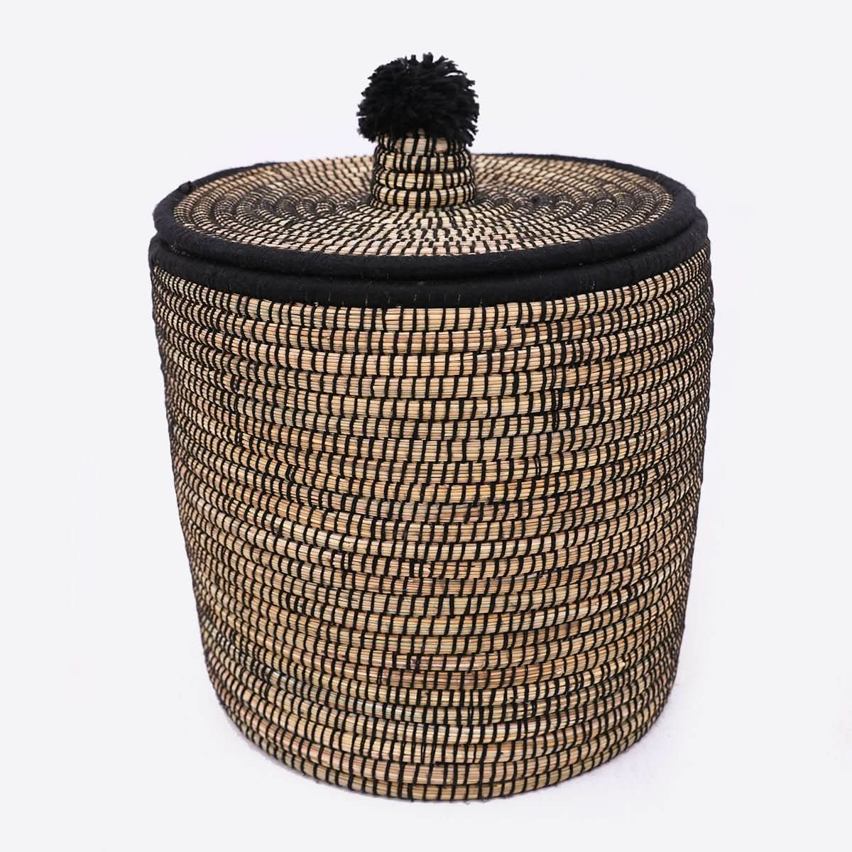 Natural rattan basket with black wool trim and pom-pom lid. Home decor.
