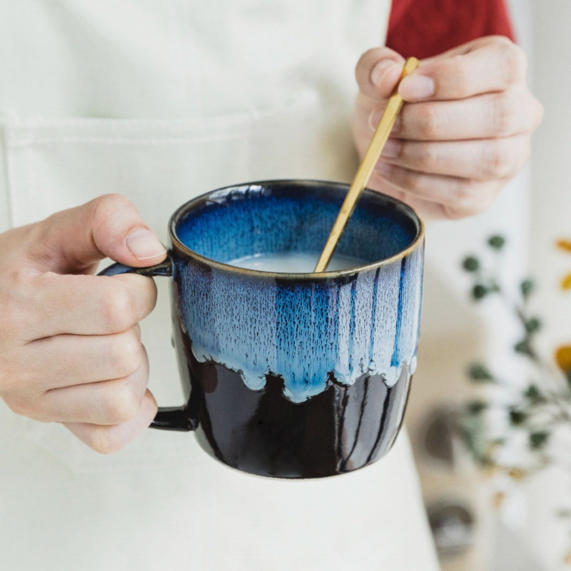 Reactive Glazed Mug 13.5oz in blue, black ceramic with a gold spoon stirring a beverage.
