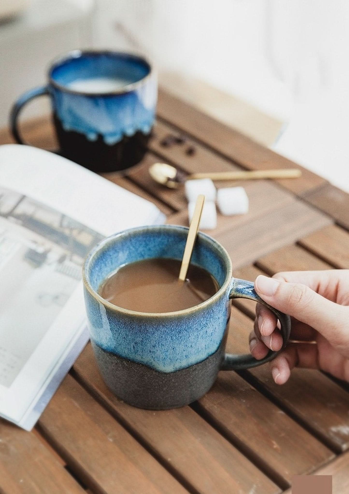 Reactive Glazed Mug 13.5oz with blue ombre glaze, ceramic, held by hand on wooden table.