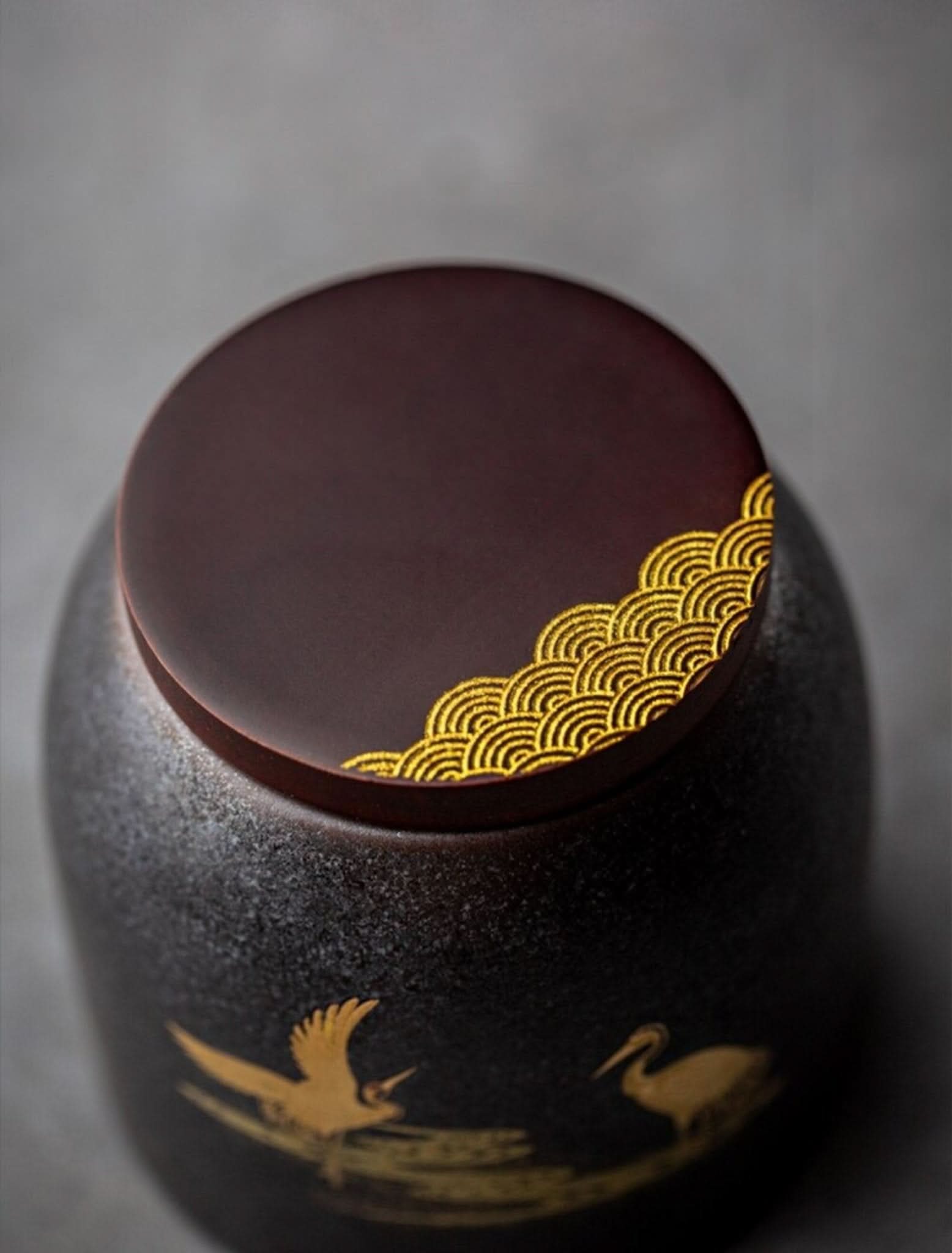 Retro black ceramic tea canister with gold wave lid detail & crane motif. Home decor accent.