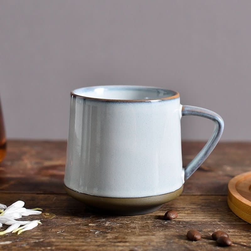 Light blue and brown glazed ceramic mug on a rustic wooden surface.