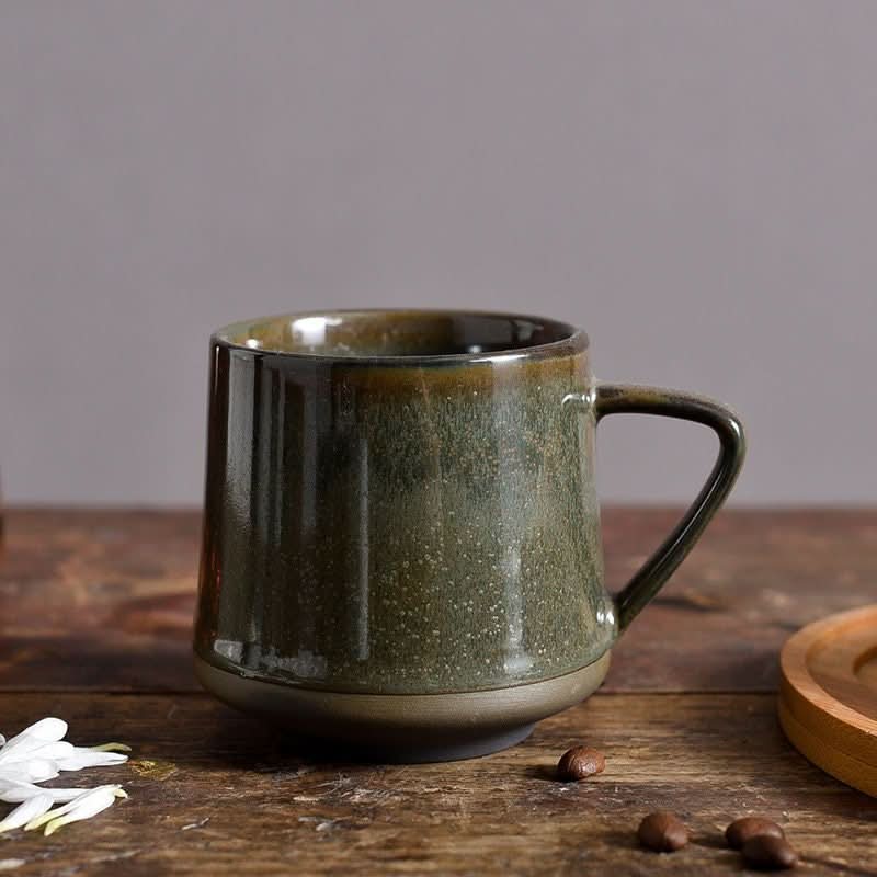 Green glazed ceramic mug with speckled finish on rustic wooden table.