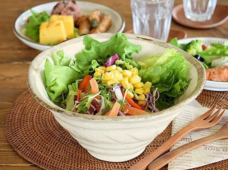 Creamy stoneware salad bowl with fresh salad, part of the Rough Pottery Stoneware Dinner Set.