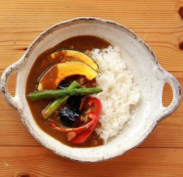 Rough pottery stoneware dinner set holding curry with rice and vegetables
