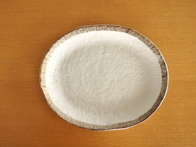 Rough Pottery Stoneware Dinner Set: cream plate with rustic brown rim on wood surface.