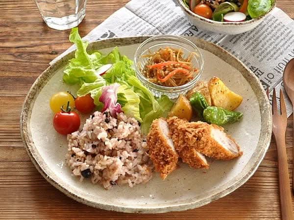 Rough pottery stoneware dinner set with a meal of chicken, rice, salad, and potatoes.