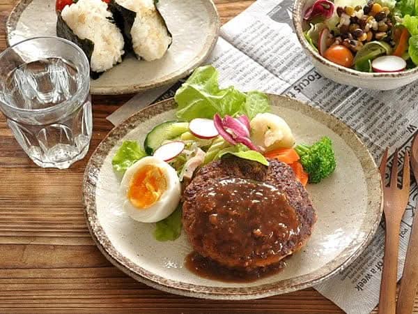 Rough Pottery Stoneware Dinner Set with hamburger, egg, and salad on a wooden table.