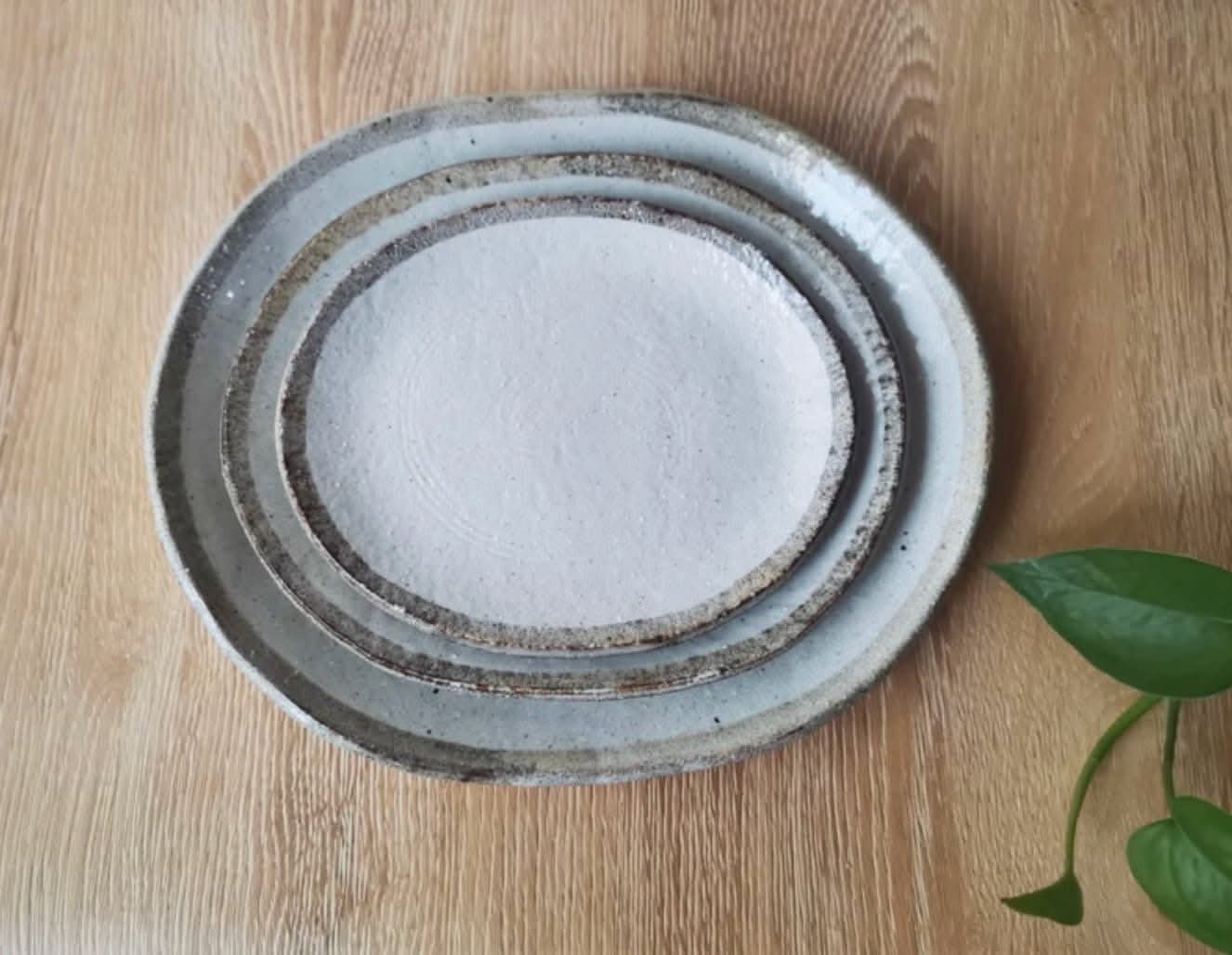 Earthy stoneware dinner set with textured rims on a wooden surface.
