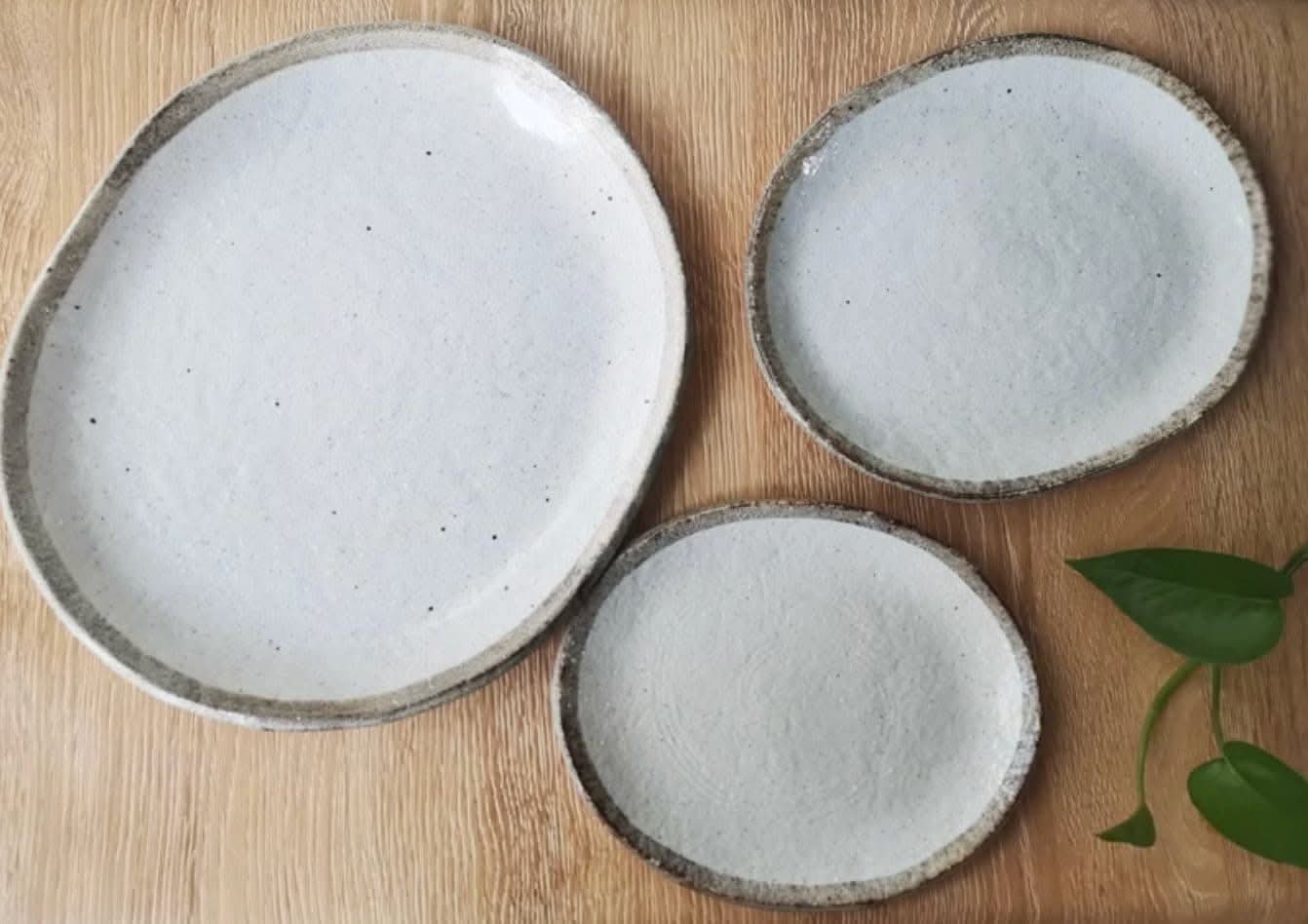 Rough pottery stoneware dinner set with textured grey rims on a wooden surface.